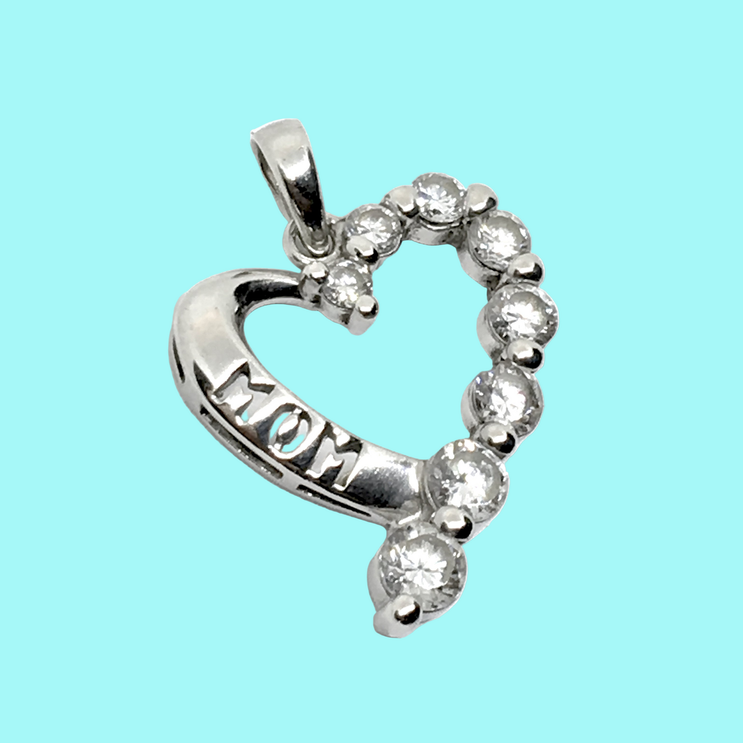 Silver heart-shaped pendant with 'MOM' engraving on a light blue background