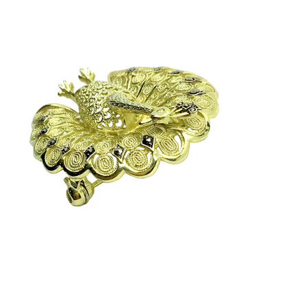 Gold peacock-shaped jewelry on a white background