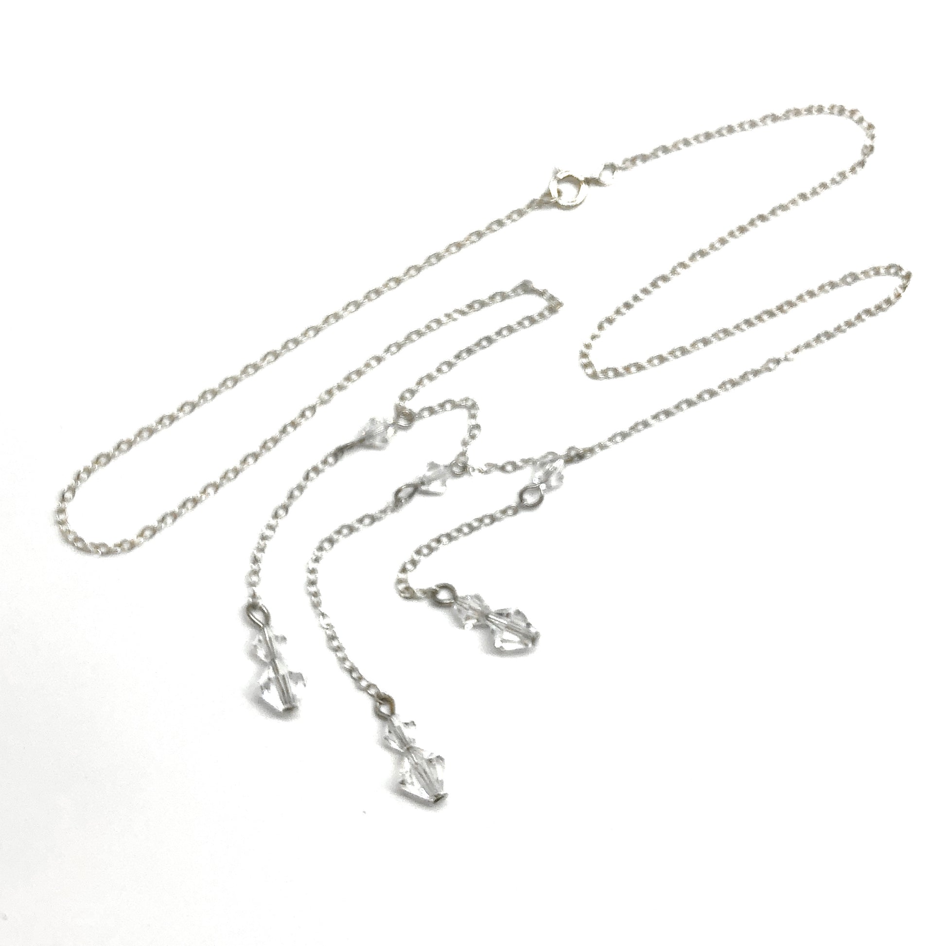 Silver necklace with three charms on a white background