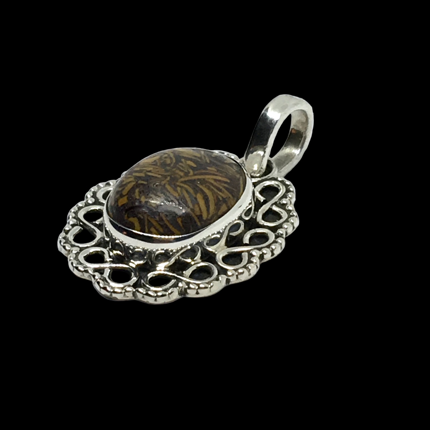 Silver pendant with intricate design on a black background
