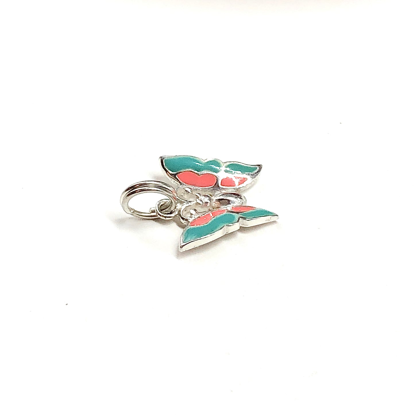 Small silver charm with green and red accents on a white background