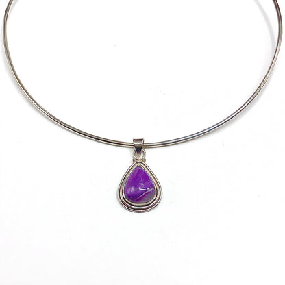 A 925 sterling silver bangle necklace with a sterling silver teardrop-shaped purple gemstone pendant. A unique color to set off any outfit.