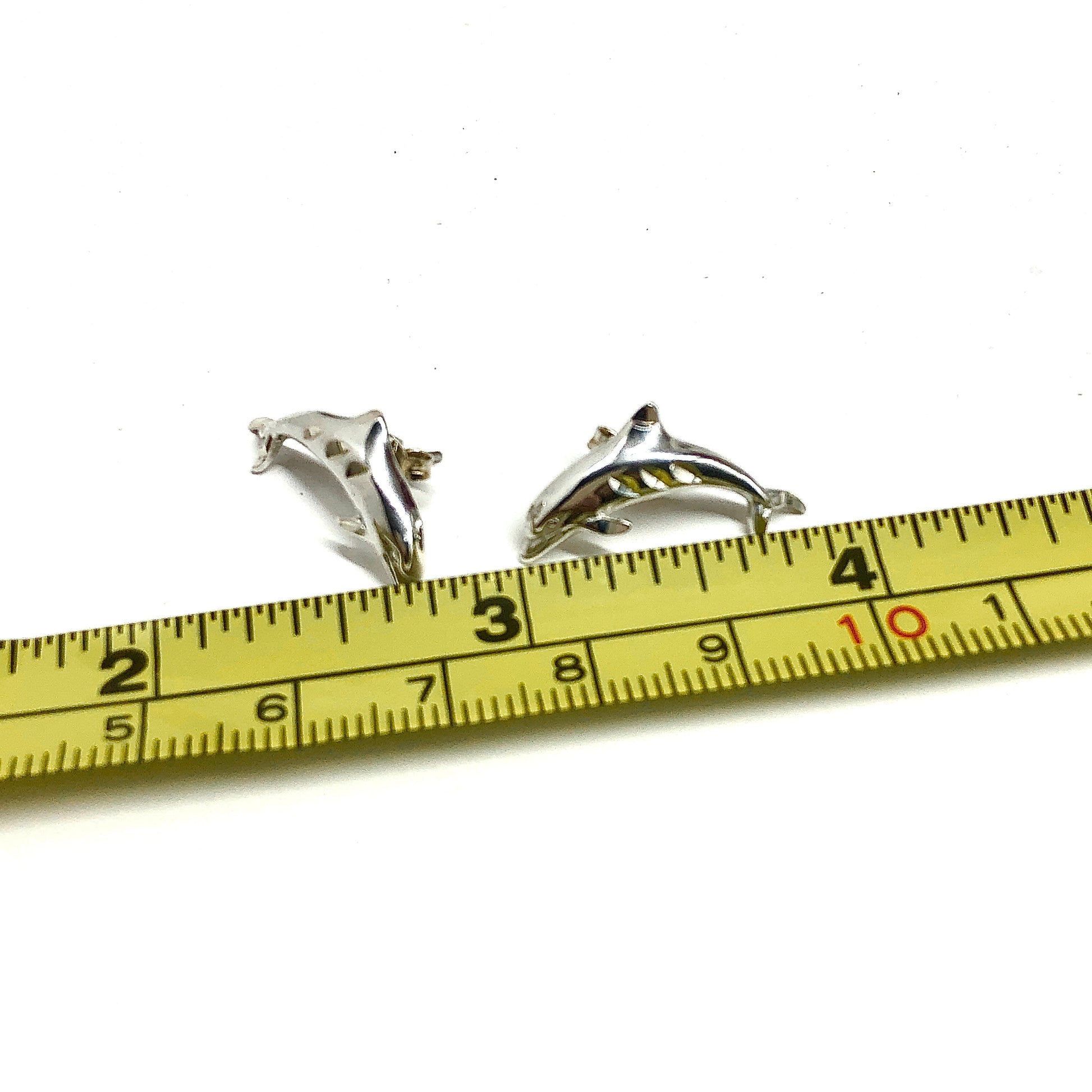 925 Silver dolphin earrings on a measuring tape against a white background for sale