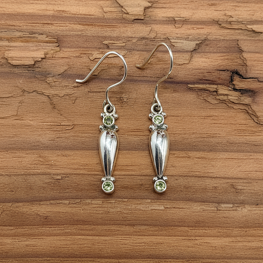 Sterling Silver earrings with green peridot gemstones on wooden table