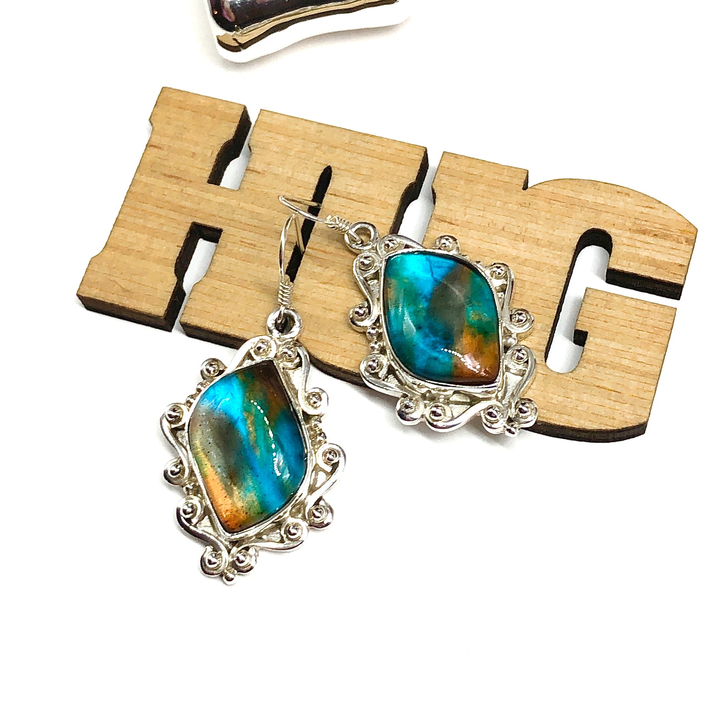 Pair of 925 Silver dangle earrings with blue and green stones on a wooden 'HUG' block background