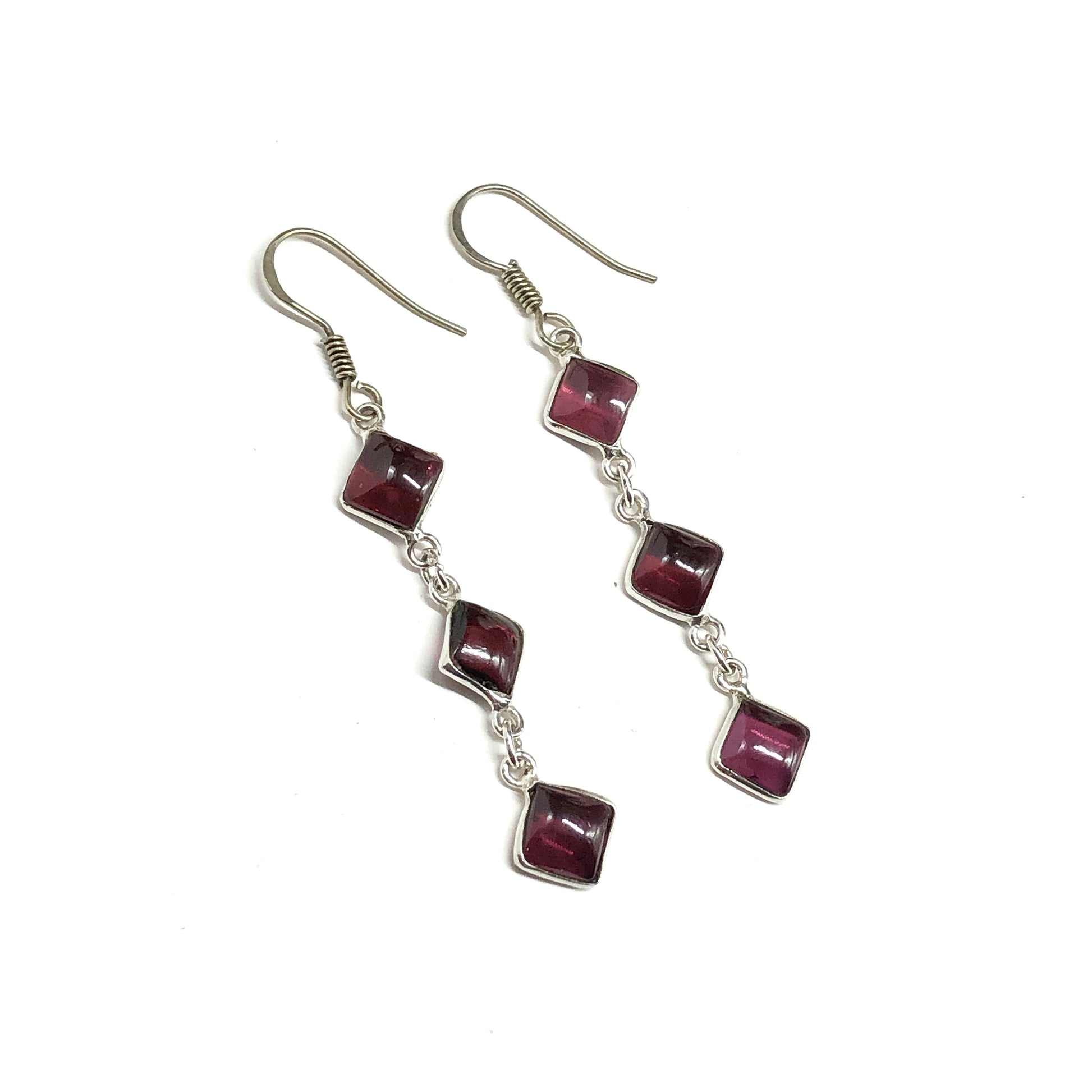 Silver earrings with red gemstones on a white background