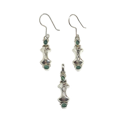 Silver earrings and pendant with green gemstones on a white background