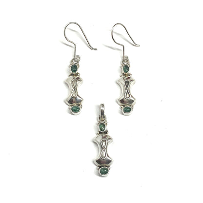 Silver earrings and pendant with green gemstones on a white background