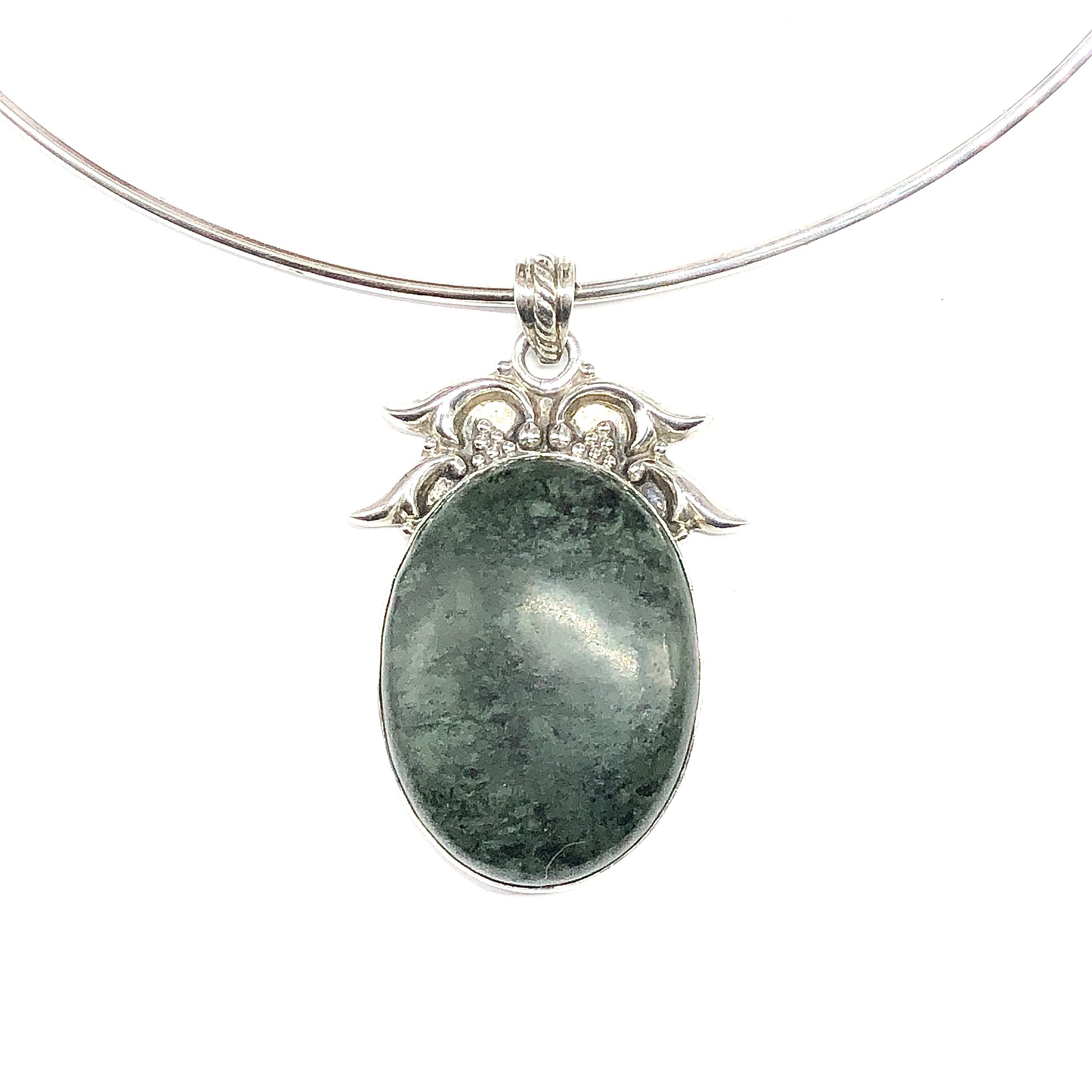 A silver necklace featuring an oval pendant with a dark green stone and an ornate silver filigree top.