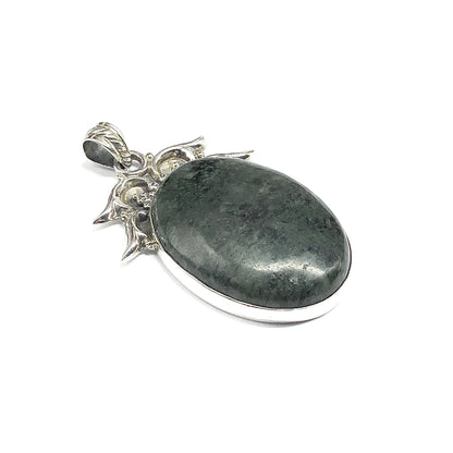 An oval pendant featuring a polished dark green stone set in a 925 silver frame with decorative leaf-like bail details.