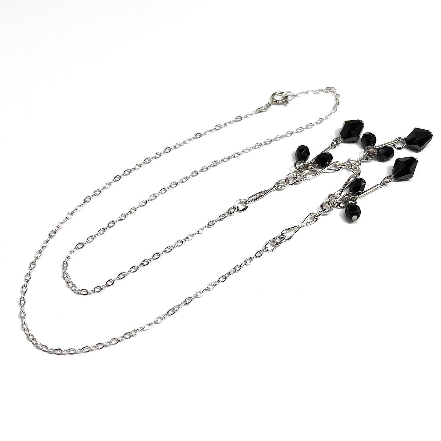 Silver chain necklace with black gemstones on a white background