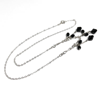 Silver chain necklace with black gemstones on a white background