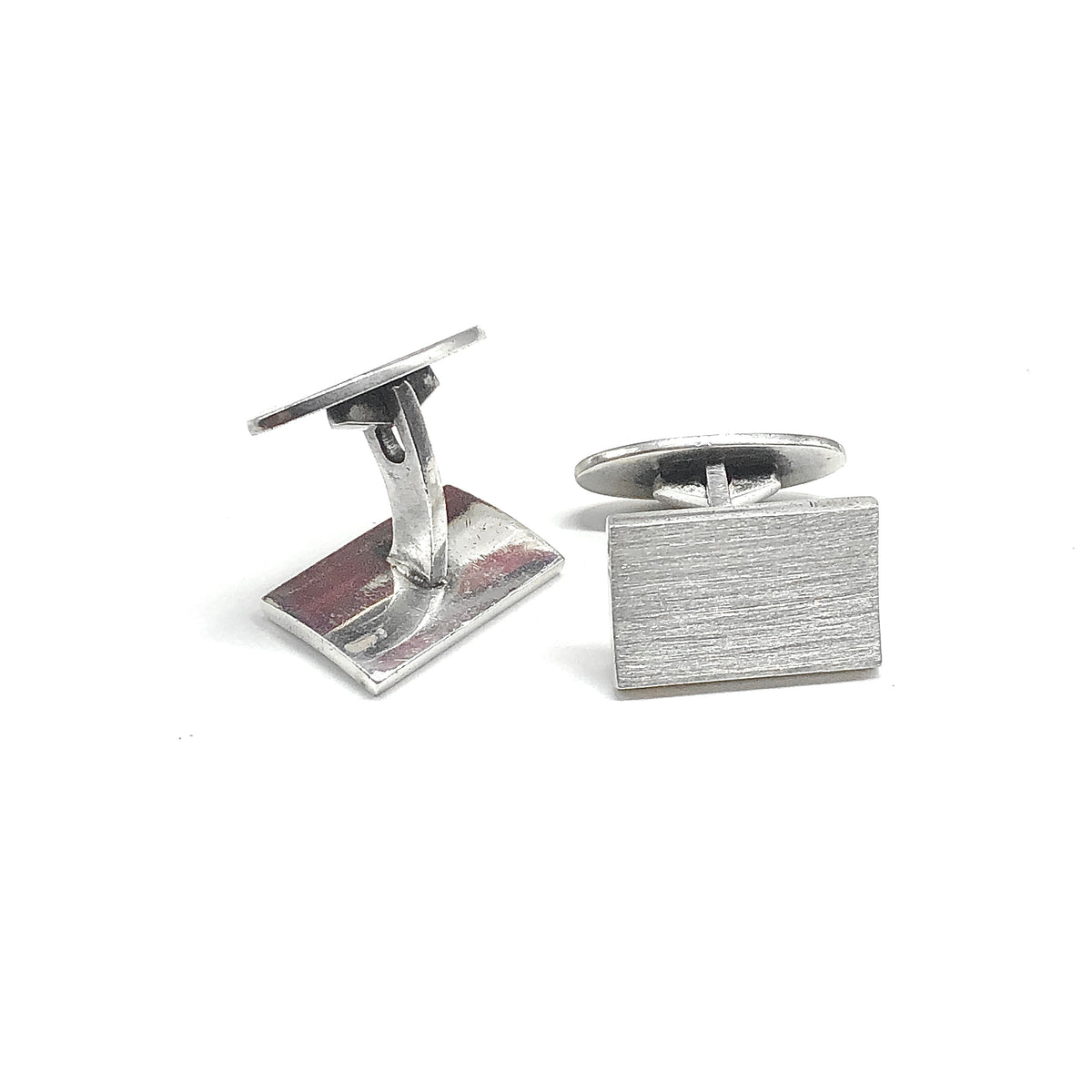 A pair of silver rectangular cufflinks with a brushed metal finish, one showing the front face and the other showing the back mechanism.
